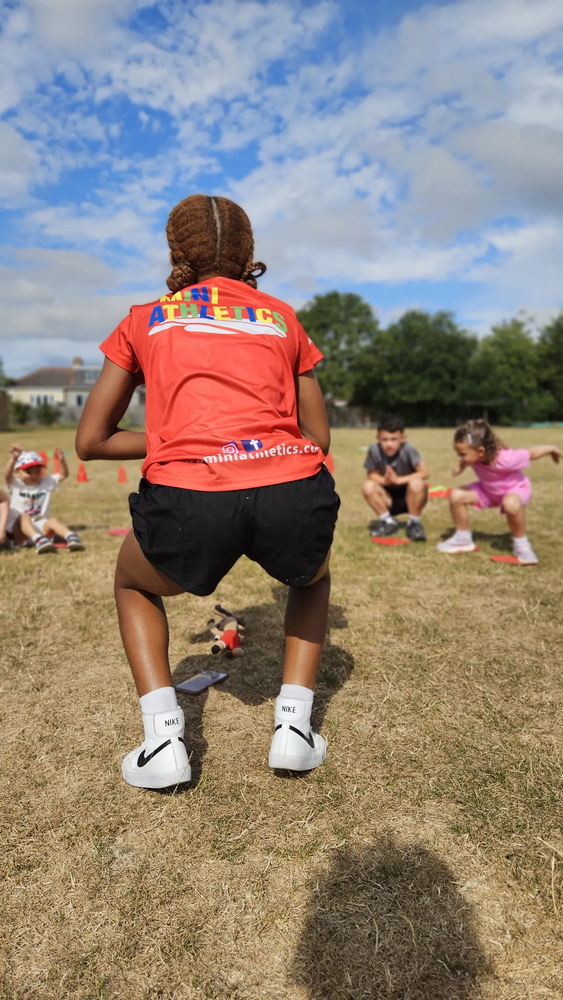 Mini Athletics coach leading an outdoor movement game at summer camp