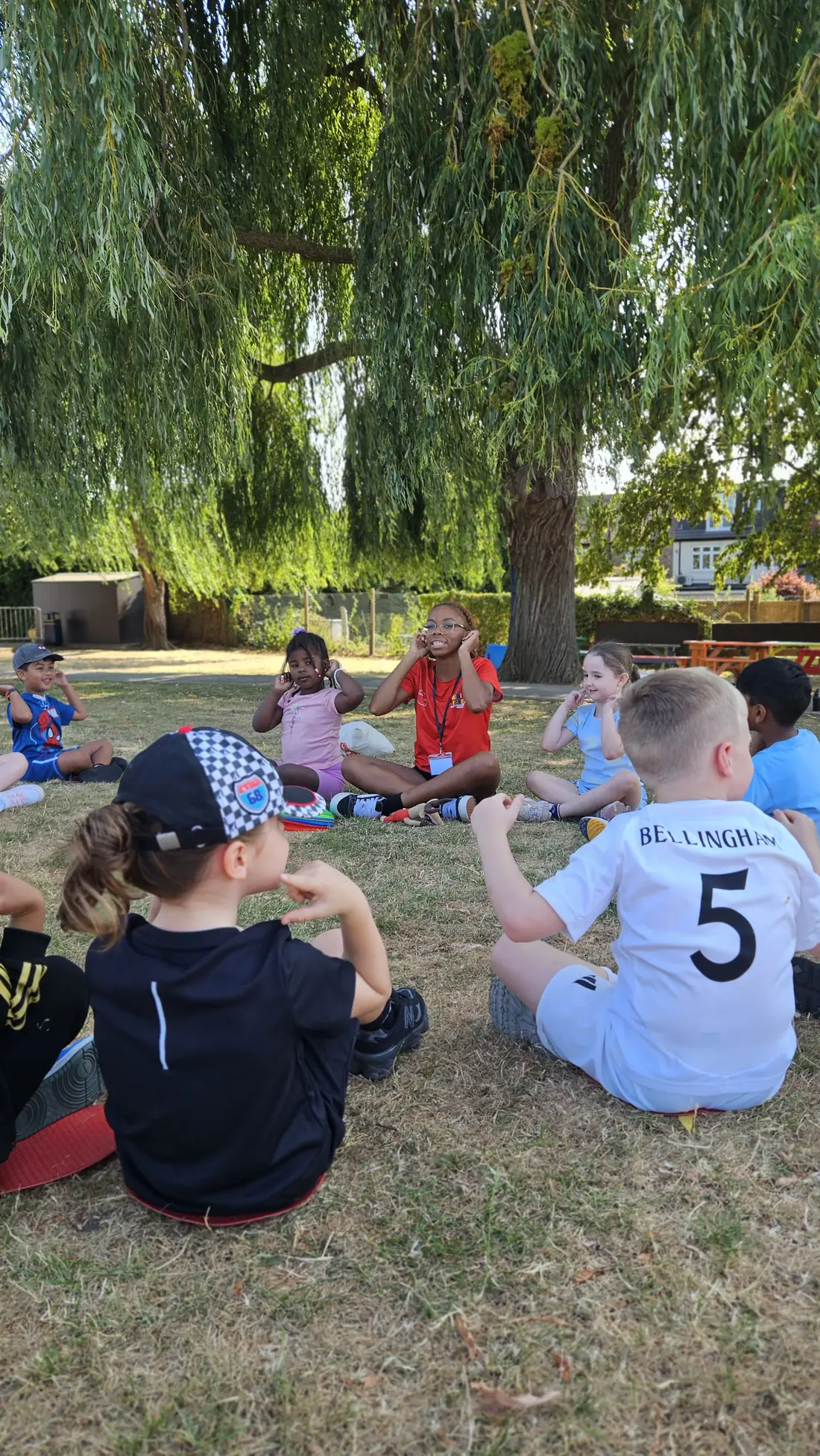 Children and a coach enjoying group time at a Mini Athletics summer camp