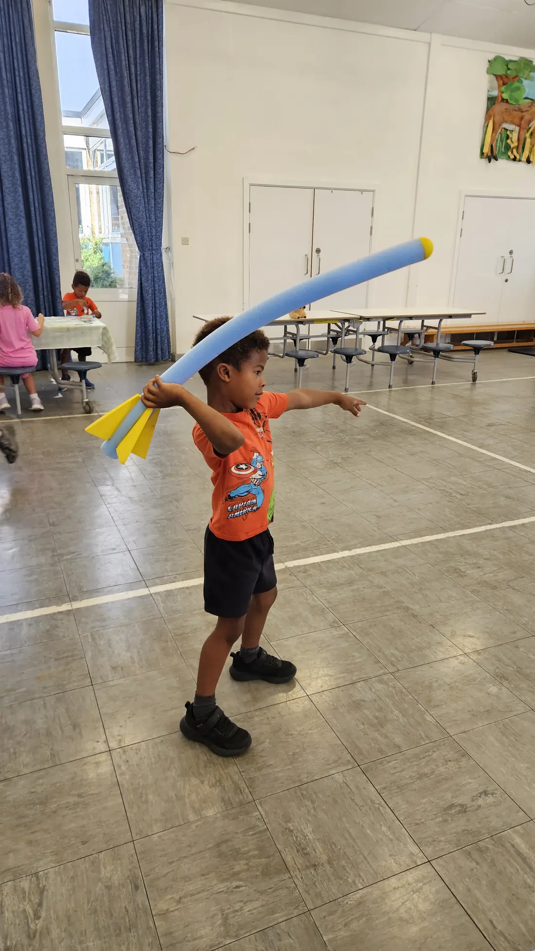Child throwing a foam rocket during a summer camp game